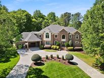 Stately brick home boasts lush landscaping, circular drive, and attached garage with a basketball hoop at 5001 Oxfordshire Rd, Waxhaw, NC 28173