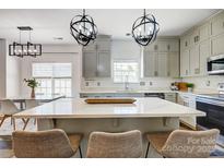 Open concept kitchen with a large island, stainless steel appliances, and modern lighting fixtures at 5713 Falkirk Ln, Matthews, NC 28104