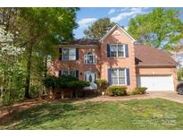 Charming brick two-story home featuring a well-maintained front yard with mature trees, and attached two car garage at 6615 Wickville Dr, Charlotte, NC 28215