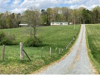 Gravel driveway leads to a single story home with green roof at 13079 Philadelphia Church Rd, Oakboro, NC 28129
