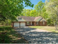 Charming brick home featuring an attached three-car garage and long driveway nestled among beautiful trees at 1478 Smith Farm Rd, Lincolnton, NC 28092