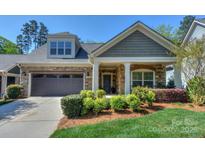 Charming home featuring stone accents, a covered front porch, and a well-maintained lawn and landscape at 14917 Dewpoint Pl, Huntersville, NC 28078