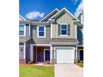 Charming townhome featuring a two-car garage, green siding, and a well-manicured front lawn at 2792 Yeager Nw Dr, Concord, NC 28027
