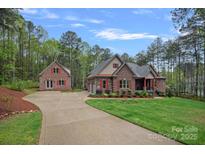 Beautiful brick home with a long driveway, lush lawn, and mature trees in a serene setting at 4637 Gold Finch Dr, Denver, NC 28037