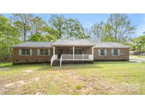 Charming brick home featuring a covered front porch and a well-maintained front yard with mature trees at 600 Community Ln, Lancaster, SC 29720