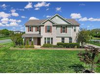 Charming two-story home featuring a well-manicured lawn and beautiful landscaping under a bright, partly cloudy sky at 610 Blaise Ct, Matthews, NC 28104