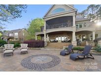 Stunning home featuring a backyard with chairs, an outdoor fireplace and lush landscaping at 20428 Island Forest Dr, Cornelius, NC 28031