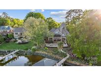 Stunning lakefront home featuring lush landscaping, a private dock, and an inviting outdoor patio at 20428 Island Forest Dr, Cornelius, NC 28031