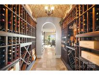 An elegant wine cellar with brick ceiling and custom wood shelving units is stocked with wines at 20428 Island Forest Dr, Cornelius, NC 28031