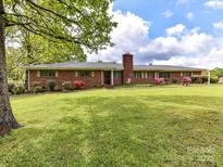 Charming brick home featuring a lush green lawn and meticulously landscaped front yard with mature trees at 225 Enwood Dr, Charlotte, NC 28214