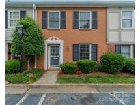 Charming brick townhome featuring black shutters, a well-manicured yard, and a welcoming blue front door at 4607 Hedgemore Dr # D, Charlotte, NC 28209