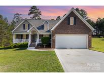 Charming brick and siding home featuring a two-car garage and inviting front porch with a manicured lawn at 5108 Boardwalk Ct, Dallas, NC 28034