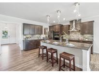 Modern kitchen boasts wood floors, granite countertops, and a large island with barstool seating at 8715 Gladden Hill Ln, Fort Mill, SC 29715