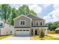 Charming two-story home featuring a two-car garage, gray siding, and a beautifully landscaped front yard at 1032 Dooley Dr, Charlotte, NC 28227