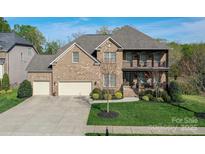 Charming brick home featuring a well-manicured lawn and inviting front porch and a three car garage at 10643 Rippling Stream Nw Dr, Concord, NC 28027