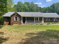 Charming brick home featuring a quaint front porch and well-maintained lawn at 1300 Irish Potato Rd, Concord, NC 28025
