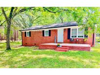 Charming brick home featuring a cozy front porch, black shutters and lovely, mature landscaping at 1780 Short St, Mount Pleasant, NC 28124