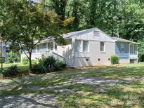 Charming single-story home with white brick, light blue siding, and a well-manicured lawn surrounded by mature trees at 2822 Royston Rd, Charlotte, NC 28208