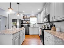 Well-lit modern kitchen boasting white cabinetry, stainless steel appliances, granite countertops, and hardwood floors at 2895 Sweeping Pine Ln, Denver, NC 28037