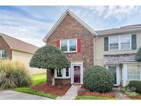 Charming brick townhome featuring a well-manicured front yard and inviting entrance with a red door and bright shutters at 8221 Pineville Matthews Rd # A, Charlotte, NC 28226