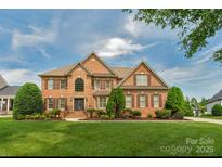 Traditional two-story brick home with well-manicured lawn, mature trees, and shuttered windows at 9008 Skipaway Dr, Waxhaw, NC 28173