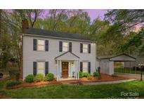 Charming two-story home with light siding, black shutters, manicured landscaping, and a detached carport at 9319 Harps Mill Ct, Charlotte, NC 28270
