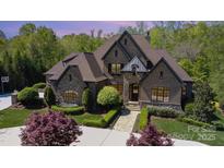An impressive brick home with stone accents, well-manicured lawn and lush landscaping create an inviting curb appeal at 1012 Shippon Ln, Waxhaw, NC 28173
