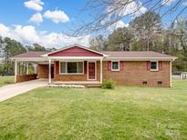 Charming single-story brick home featuring a well-maintained front yard, cozy front porch, and a convenient side carport at 103 Alexis Forest Dr, Stanley, NC 28164