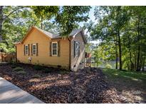 Cozy waterfront home with brown siding, white window trim, stone foundation, and mature trees at 119 Harbor Ln, Mount Gilead, NC 27306
