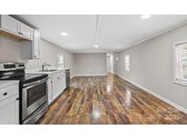 Open-concept living area with wood-look floors and stainless steel appliances at 170 Dusty Loop Dr, Mount Gilead, NC 27306