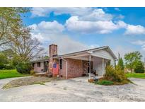 Ranch-style brick home with an attached carport and a charming front yard, enhanced by a classic brick chimney at 1910 York Hwy, York, SC 29745