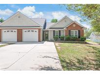 Charming home featuring an attached two car garage, brick facade, and well manicured lawn at 219 Edinburgh Ct, Mount Holly, NC 28120