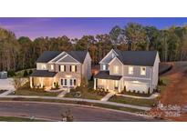Two beautiful new construction homes with manicured lawns on a peaceful street at dusk at 7105 Short Stirrup Ln, Mint Hill, NC 28227