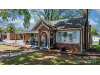 Quaint brick home featuring a covered front porch with rocking chairs and tidy landscaping at 2701 N Main Ave, Newton, NC 28658