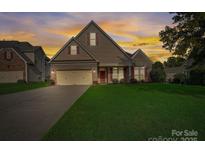 Charming two-story home with brick accents, green lawn, and an attached two-car garage at sunset at 6024 Berewick Commons Pkwy, Charlotte, NC 28278