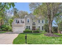 Charming two-story home with a manicured lawn, mature trees, and a two-car garage at 7316 Versailles Ln, Charlotte, NC 28277