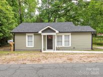 Charming single-story home with light green siding, black front door, and well-maintained yard with small decorative fence at 803 E 13Th St, Kannapolis, NC 28083