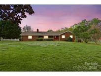 A charming brick home features a lush green lawn and a warm, inviting ambiance at dusk at 173 Chestnut Grove Rd, Statesville, NC 28625