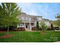 Charming two-story home with manicured lawn, gray siding, stone accents and welcoming front porch at 4205 Green Park Ct, Harrisburg, NC 28075