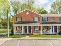 Charming brick townhome featuring a covered front porch and landscaped yard at 1217 Green Oaks Ln # K, Charlotte, NC 28205