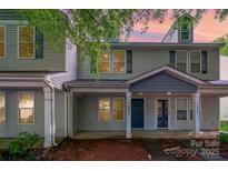 Charming two-story townhome with covered front porch and neutral siding at dusk at 12925 Windy Lea Ln, Huntersville, NC 28078