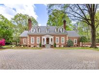 Stately brick home featuring dormer windows, a brick chimney and a large brick-paved driveway at 1441 Carmel Rd, Charlotte, NC 28226