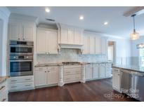 Bright kitchen features stainless steel appliances, white cabinetry, granite counters, and a tile backsplash at 8810 Cool Meadow Dr, Huntersville, NC 28078