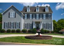 Traditional two-story home with gray siding, black shutters, manicured landscaping, and a circular fountain in the front yard at 143 S Gibbs Rd, Mooresville, NC 28117