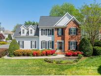 Charming two-story home with a combination of white siding and brick, complemented by a lush, landscaped front yard at 16718 Hampton Crossing Dr, Huntersville, NC 28078