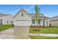 Charming single-Gathering home featuring a two-car garage, manicured lawn, and modern architectural details at 8432 Norman Forest Rd, Lancaster, SC 29720