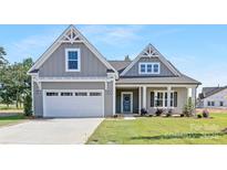 Charming home exterior features a well-manicured lawn, a two-car garage and inviting front porch at 908 Cypress Point Ln # 218, Monroe, NC 28112
