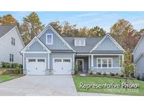 Charming craftsman-style home with a two-car garage and inviting front porch, nestled amongst mature trees at 908 Cypress Point Ln # 218, Monroe, NC 28112