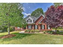 Charming brick home boasts mature trees, lush landscaping, and a well-manicured lawn, exuding curb appeal at 1090 Heather Glen Dr, Matthews, NC 28104