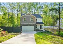 Charming two-story home with a stone-accented garage, concrete driveway and landscaped front yard at 11040 E Lake Rd, Charlotte, NC 28215
